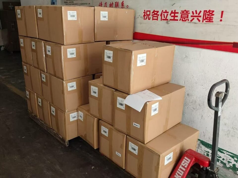 Cartons stacked by a warehouse door with a pallet jack